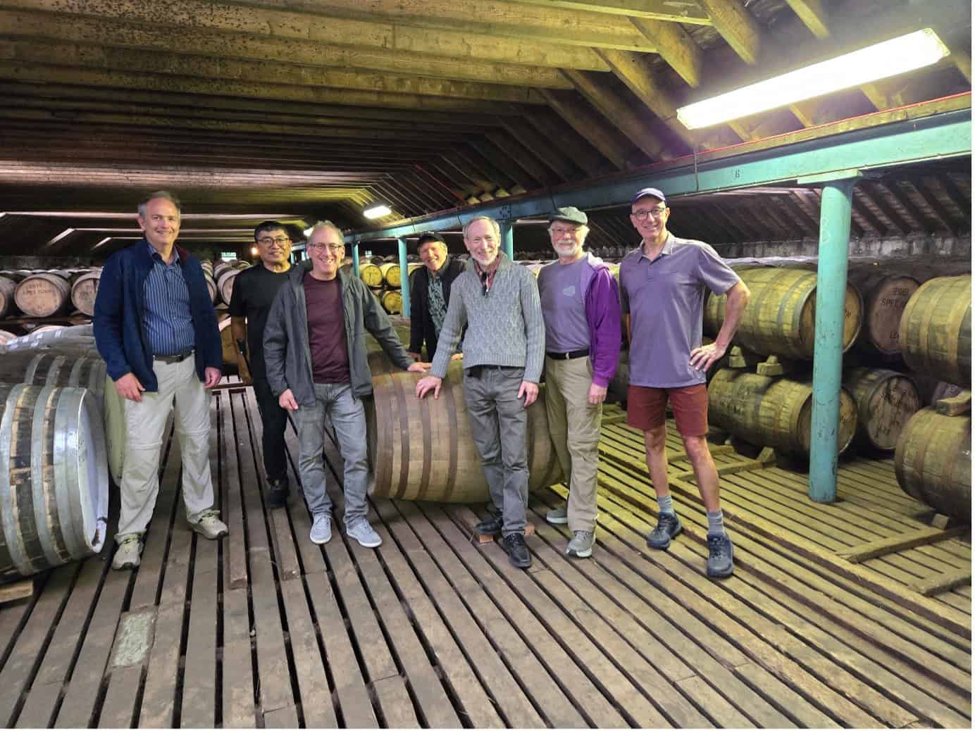 A photo of Allen and his travel companions standing next to whisky barrels in a bonded warehouse